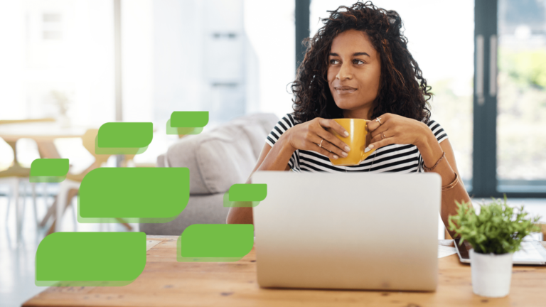 A young Black woman sitting in front of her computer holding a cup of coffee and looking to the left