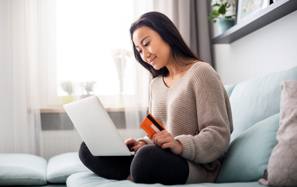 Image of woman sitting on sofa with credit card and laptop