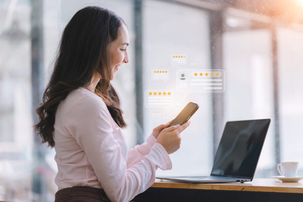 woman at a workstation responding to customer reviews on her phone