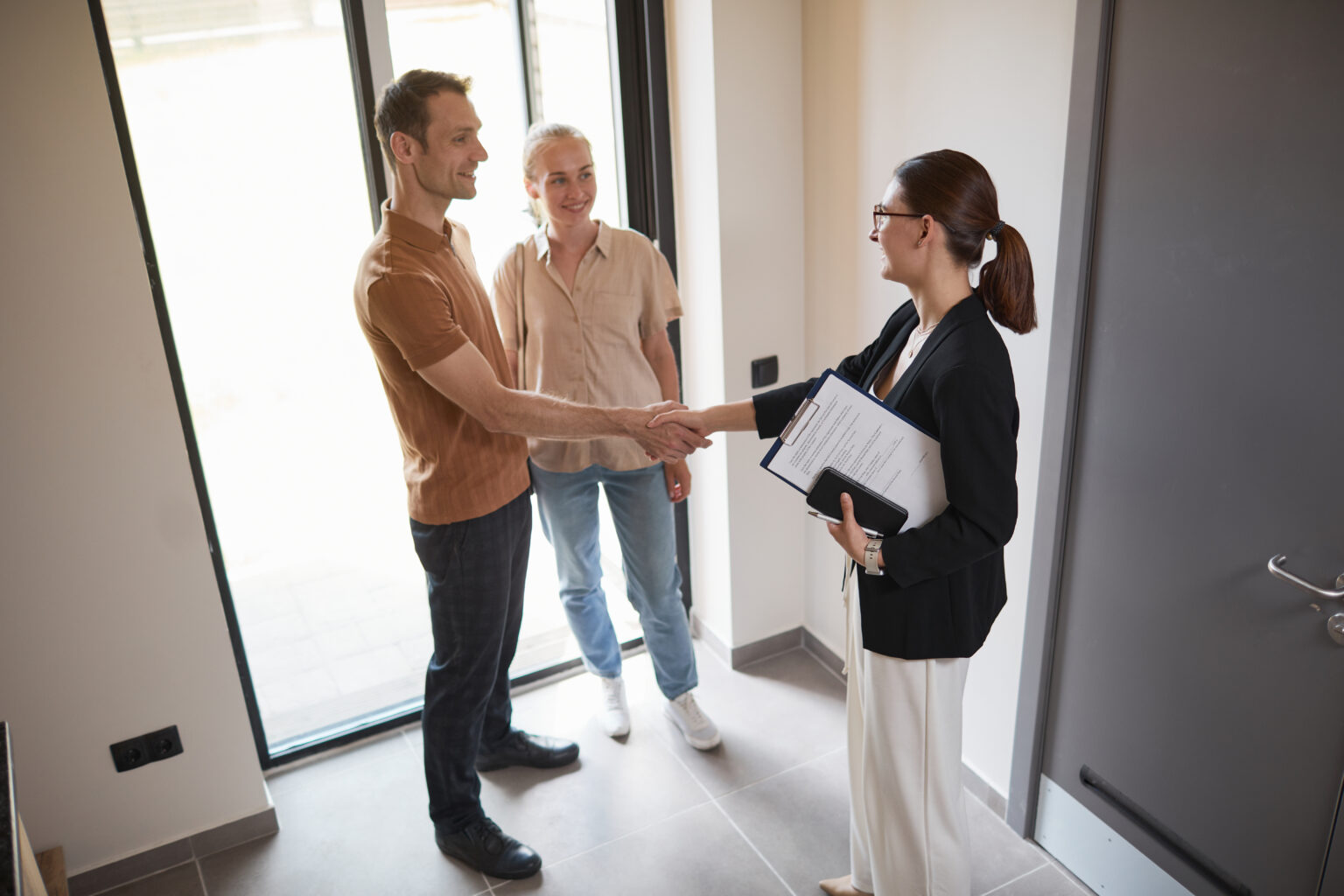 Real estate agent shaking hands with clients