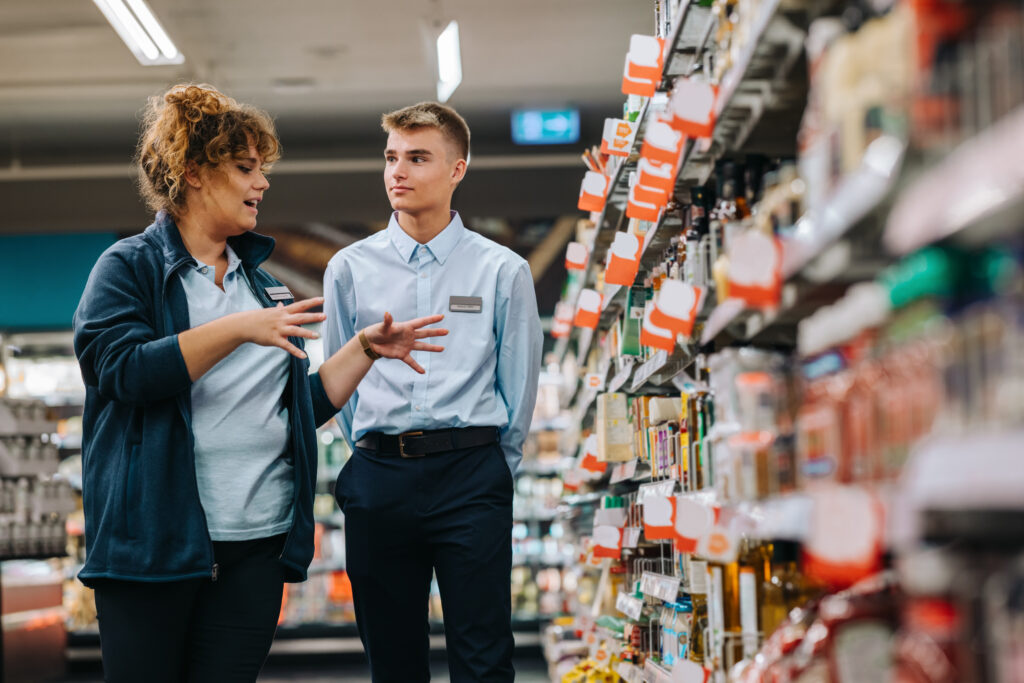 Store manager speaking to her employee while standing in an aisle